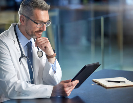  a mature doctor using a digital tablet in his office.