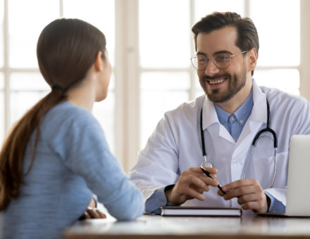 Smiling man doctor consult woman client at meeting in clinic